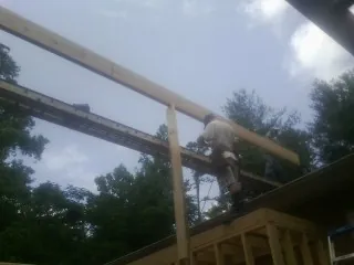 Carpenter setting a ridge beam over a new addition frame — Ice Dam Removal by Roofing Brothers in Manitou