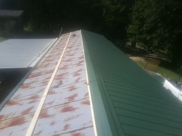 Old rusted panels beside newly installed green metal roofing — Wind Damage Roof Repair by Roofing Brothers in Manitou