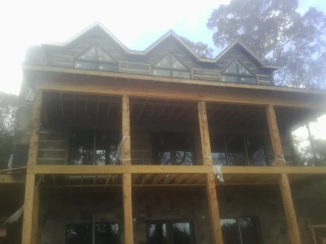 Dormers and porch framing on a large log home under construction — Roof Coating work by our crew in Manitou