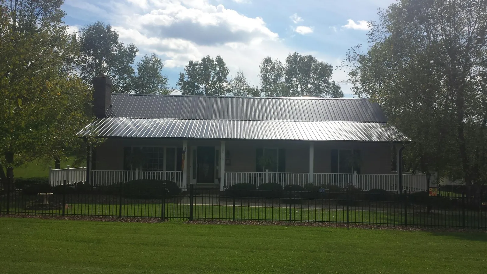 Gray metal roof on a brick ranch with a full width front porch — Gutter Guard Installation work by our crew in Manitou
