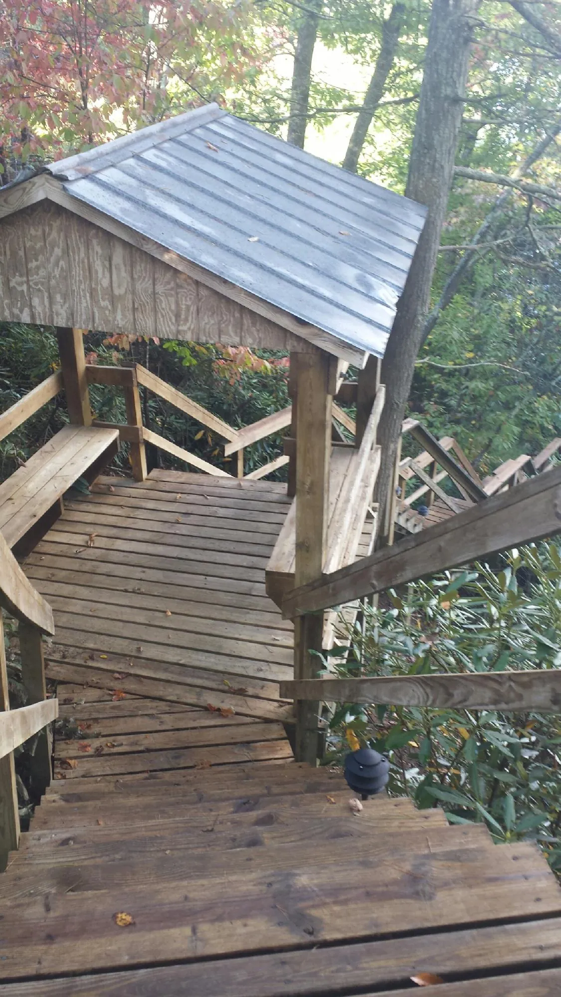 Metal roofed shelter over wooden steps on a wooded walkway — Skylight Repair & Installation work by our crew in Manitou